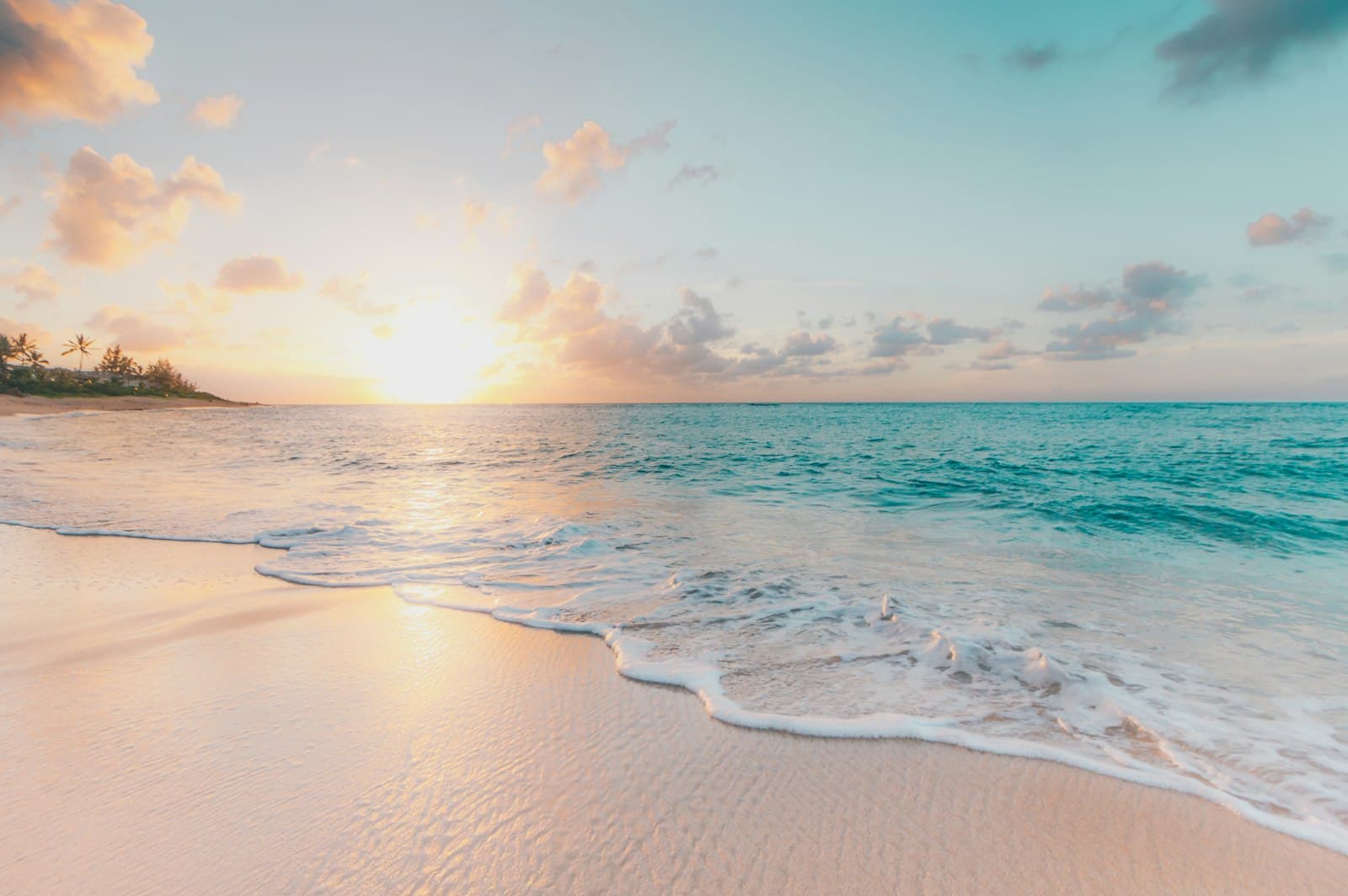La plage de sable blond au couchant, écume rose et mer turquoise