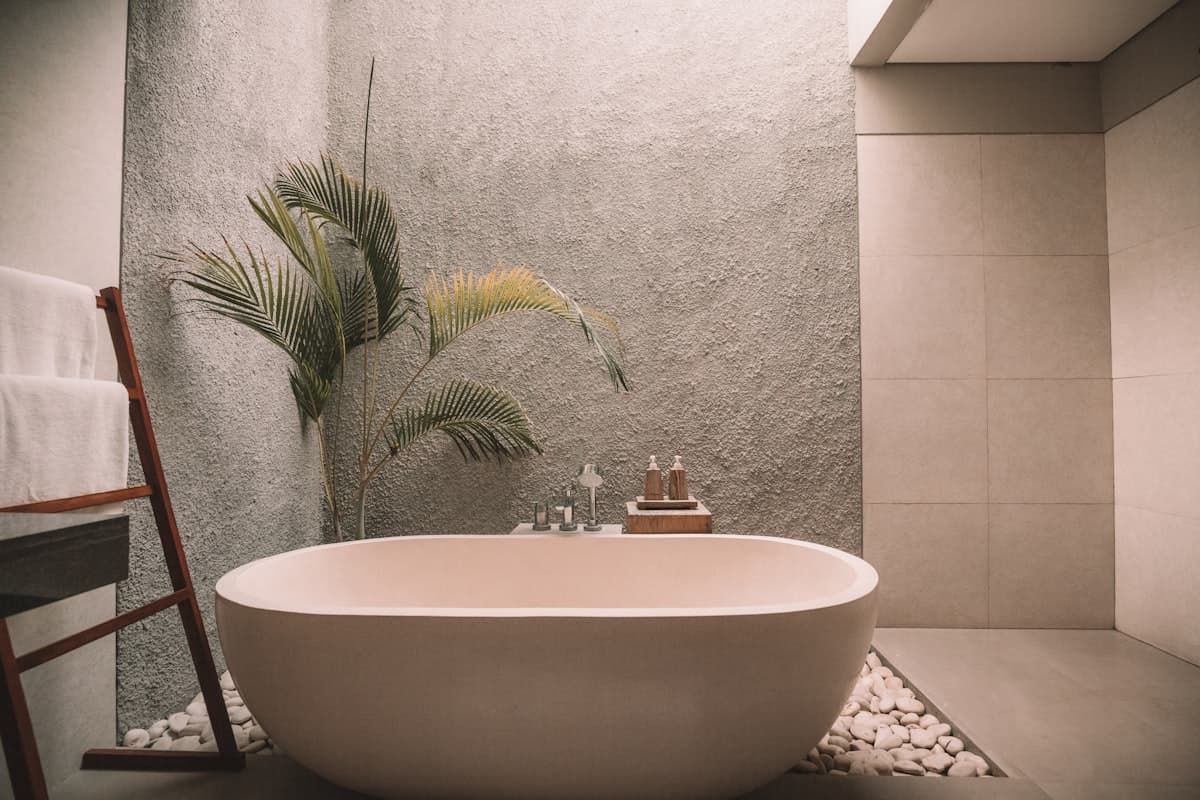 Baignoire îlot en pierre claire de la Suite Corniche, galets blancs et palme