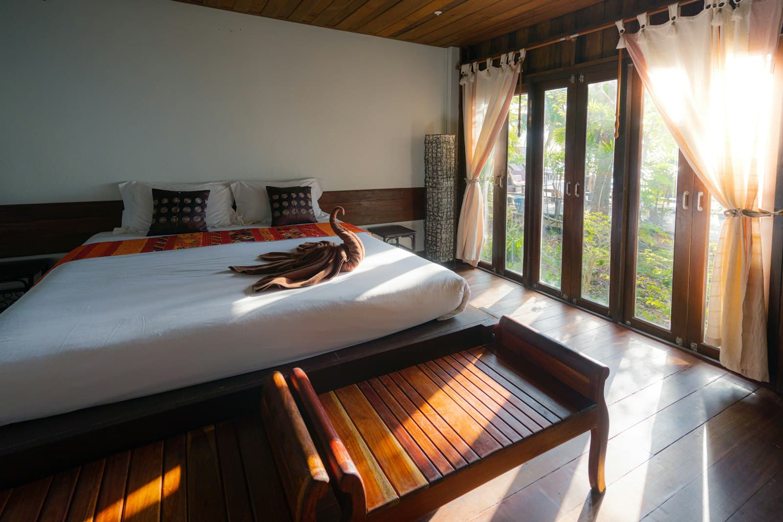 Chambre de la Suite Corniche au lever du soleil, baies vitrées ouvertes sur la verdure